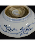 Blue and white porcelain bowl upside-down, hand painted with florals, showing worn circular base mark.