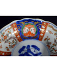 Red, blue, green, and gold hand painted Imari porcelain bowl with floral patterns, close-up view.