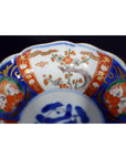 Close-up of blue, red, and gold floral Japanese Imari porcelain bowl with unique central scene.