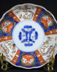 Close-up of a hand painted Japanese Imari porcelain bowl with vibrant floral patterns on a gold stand.