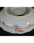 White porcelain bowl bottom with blue and orange floral designs, close-up, hand painted Japanese Imari style.