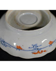 Blue and orange porcelain bowl with floral designs, upside down on a black surface.