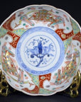Close-up of red, blue, and gold hand painted Japanese Imari porcelain bowl with blue floral center motif.