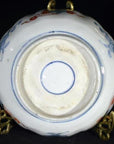Close-up of the underside of an antique hand painted Japanese Imari porcelain bowl on a brass stand.