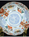 Close-up of a red, blue, and gold hand painted Japanese Imari porcelain bowl on a brass stand.