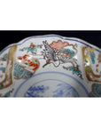 Close-up of antique hand painted Japanese Imari porcelain bowl with crane and red, teal, and gold floral designs.