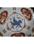 Close-up of antique hand painted Japanese Imari porcelain plate with floral patterns and blue mythical creature centerpiece.
