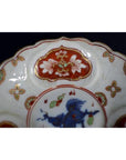 Close-up of an antique Japanese Imari porcelain plate with red, white, blue, and green floral and bird designs.