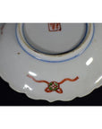 Close-up of bottom of antique Japanese Imari porcelain plate, red and green painted designs, central red stamp.