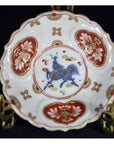 Close-up of blue and red hand painted Imari porcelain plate with gold rim and mythical animal motif.
