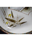 Close-up of antique hand painted Japanese Kutani porcelain bowl with yellow flowers and vintage patterned edge.