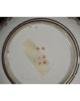 Close-up of the bottom of a Kutani porcelain bowl with red marks, tape, and visible antique hand painted details.