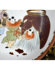 Close-up of antique hand painted Japanese Kutani porcelain plate with green-clad figure aiding another from gold-trimmed jar.