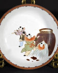 Close-up of antique Japanese Kutani porcelain plate, hand painted with three children in traditional dress by brown jar.