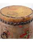 Close-up of faded, hand-painted wood and leather drum with metal studs and floral pattern.