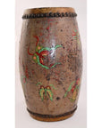 Brown wood and leather drum with hand painted floral designs and metal studs on top and bottom edges, close-up.