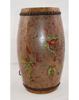Close-up of antique wood and leather drum with red and green floral hand-painted designs and decorative edge studs.