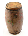 Brown wood and leather drum with faded painted designs, metal studs on top, and metal rings on sides.