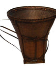 Brown rattan cone-shaped basket with two back straps, plain background.