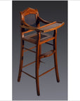 Brown wooden antique highchair with rattan back, tray table, and footrest against a dark background.
