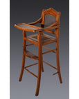Dark wood and rattan antique highchair with tray and footrest, displayed against a plain dark background.