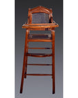 Brown rattan and wood antique highchair with woven seat, set against a dark background.
