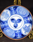 White porcelain Igezara transferware plate with blue floral and geometric patterns on a decorative gold stand.