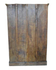 Brown wood panel close-up with visible grain, rustic finish, resembling an antique Indian cabinet carved door.