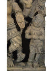 Brown sheesham wood temple decoration featuring a small stone figure with folded hands beside a larger figure’s limb.