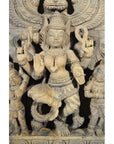Brown sheesham wood hand-carved temple decoration with ornate multi-armed Hindu deity, close-up view.