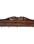 Close-up of red, gold, and green hand-carved wooden Indian wall ornament with intricate floral and leaf patterns.
