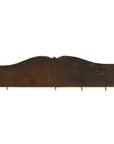 Close-up of a rustic, dark-stained wood Indian hand-carved wall ornament against a white background.