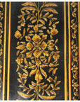 Gold and yellow floral patterns on black wood, antique Indian lacquered door close-up.