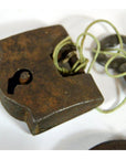 Close-up of antique Indian brass locks with original key tied by string on a white background.