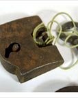 Close-up of antique Indian brass locks with original key tied by string on a white background.