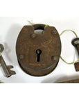 Close-up of antique metal Indian locks with original keys tied by string, displayed on a white surface.
