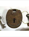 Close-up of antique metal Indian locks with original keys tied by string, displayed on a white surface.