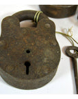 Close-up of antique brass Indian locks and a key tied with string on a white background.