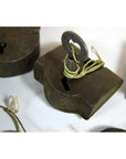 Close-up of an antique metal Indian lock with an old key tied by string, resting on a white surface.