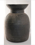 Close-up of large dark handmade Indian milk storage container with horizontal grooves and wide flared rim.