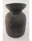 Close-up of a dark antique Indian metal milk storage container with wide flared rim and textured horizontal lines.