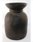 Black metal antique Indian milk storage container with wide rim and horizontal grooves, close-up.