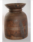 Close-up of rustic brown antique Indian milk storage container with carved lines and wide rim on a light background.