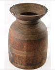 Close-up of a brown wooden antique Indian milk storage container with horizontal carved grooves and wide rim.