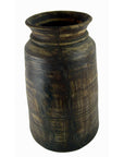Dark brown antique Indian milk storage container, cylindrical with cracks and horizontal textured lines, close-up view.