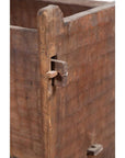 Close-up of brown weathered wood joint with peg on rustic wooden planter, showing chiseled surface texture.