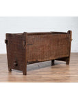 Brown weathered wood planter with chiseled texture on wooden floor.
