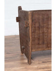 Close-up of a weathered wooden planter with chiseled texture on a wooden floor against a white wall.