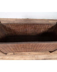 Brown weathered wood rectangular planter with side handles, on wooden floor against a white wall indoors.