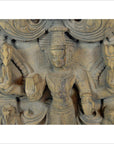 Brown Sheesham wood carving, close-up of a multi-armed deity with jewelry, headdress, and symbolic objects.